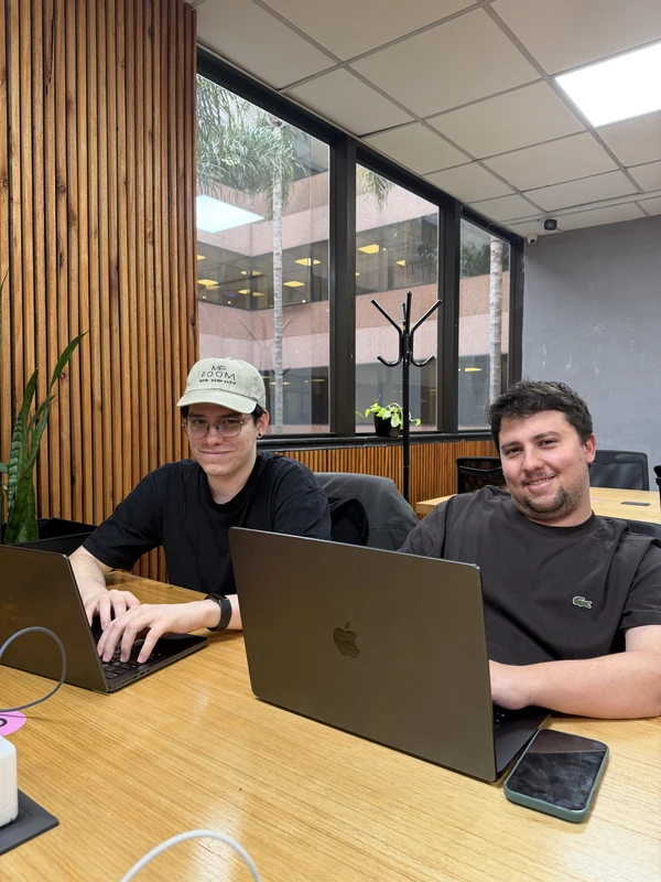 Two colleagues working at an open laptop beside a wood-panelled wall