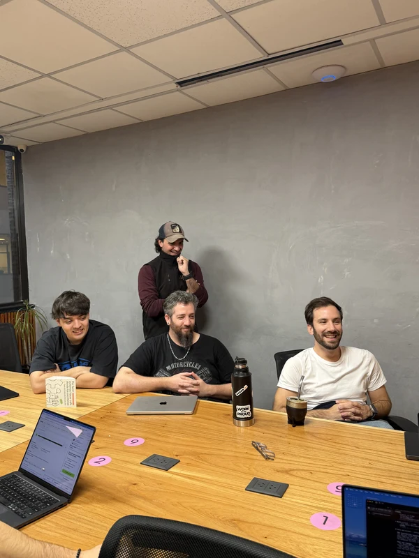 Colleagues gathered around the meeting table with their laptops open