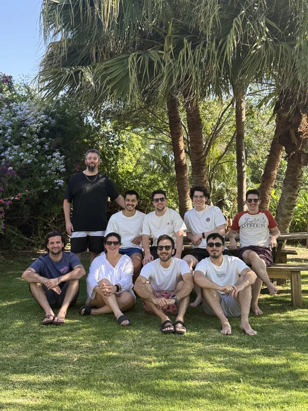The team sitting together on the grass among palm trees